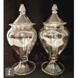 A pair of late 19th Century clear crystal glass storage jars with a folded conical foot,