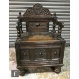 A Victorian carved dark oak monks style chair with lift seat carved 'Rest Here' below a panelled