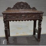 A Victorian dark carved oak side table, the moulded edge over a frieze lion mask handled drawer,