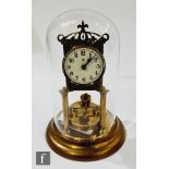 An early 20th century 365 day brass mantle clock in glass dome, the circular dial and back plate