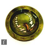 A late 19th Century shallow bowl decorated with tubelined foxgloves and foliage against a green