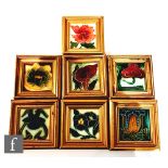 Seven assorted framed 3in Art Nouveau dust pressed tiles, each with a stylised flower head to