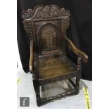 An 18th Century carved oak Wainscot chair, the scroll carved rail over a panelled back detailed with