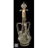 An Edwardian clear crystal decanter of footed low shouldered form with three applied angular handles