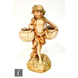 An early 20th Century Royal Dux model of a boy holding two baskets over his shoulders, with a