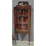 An Edwardian mahogany bow fronted display cabinet enclosed by a leaded light blue coloured glass