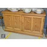 A stripped pine dresser/cupboard base, the fitted shelf interior enclosed by a pair of panelled