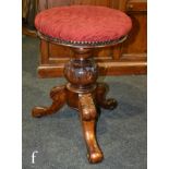 A Victorian carved walnut adjustable piano stool with revolving circular top in crimson plush,