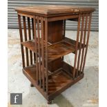 An early 20th Century walnut revolving bookcase of square form, with slender lath panel sides over a