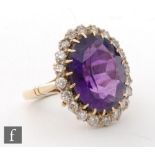 An 18ct amethyst and diamond cluster ring, central oval amethyst, length 16mm, within a border of