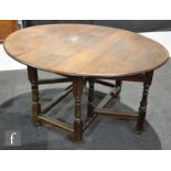 An 18th Century and later oak oval gate leg dining table on turned baluster legs united by rail