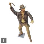 A life size painted fibre glass mannequin of Indiana Jones dressed in the classic outfit with hat,