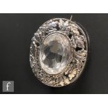 An Arts and Crafts sterling silver oval brooch set with central rock crystal within a pierced oak