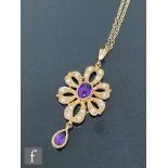 A 9ct amethyst and seed pearl set pendant, central amethyst within a pierced seed pearl scroll
