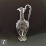A late 19th to early 20th Century claret jug of footed ovoid form with slender slice cut neck and