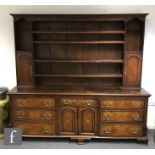 A George III crossbanded oak dresser, the panelled cupboard back on a base enclosed by a pair