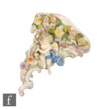 A continental wall bracket in the Meissen style modelled with a cherub sat on rococo scrolls with