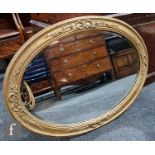 A 20th Century oval gilt bevelled glass wall mirror with raised design of a bow and leaf border,