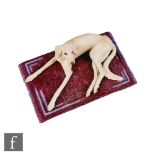A later 20th Century model of a seated greyhound type dog sat on a maroon rug, unmarked, probably