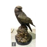 A large contemporary bronze sculpture of a falcon, perched on a naturalistic rocky outcrop, with