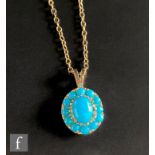 A 9ct turquoise cluster pendent, central oval turquoise within a conforming twelve stone border,