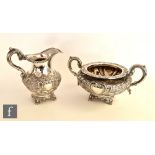 A Victorian matched hallmarked silver cream jug and sugar basin, each raised on four scroll feet and