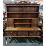 An 18th Century and later carved oak dresser, the scroll shaped cupboard back over a base fitted