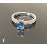 A hallmarked 18ct white gold sapphire and diamond ring, central emerald cut claw set sapphire,