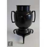 A Japanese bronze vase, the ovoid form vase flanked with twin angular handles and raised on a tripod