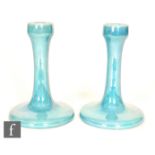 Ruskin Pottery - A pair of candlesticks of typical form decorated in an all over blue lustre,