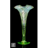 A late 19th Century glass vase of wrythen trumpet form with wave rim, all in a graduated green