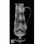 A Victorian glass jug of footed tapering form, profusely engraved with bands of leaves and