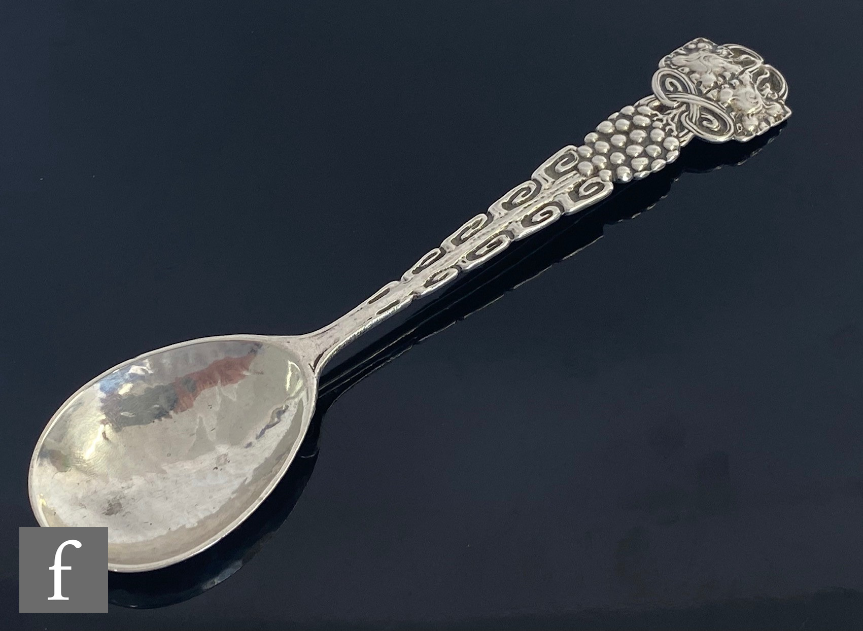 An Arts and Crafts hallmarked silver spoon decorated with berries below stylised leaf details