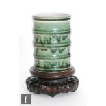 A Chinese green glazed brushpot, the bamboo form cylindrical pot with streaked green glaze over a