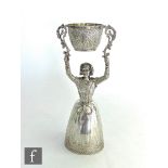 A modern hallmarked silver wager cup modelled as a women with arms raised supporting a small bowl,