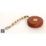 A mid 20th Century 50ft tape measure with central brass winder to a leather case, diameter 12cm,