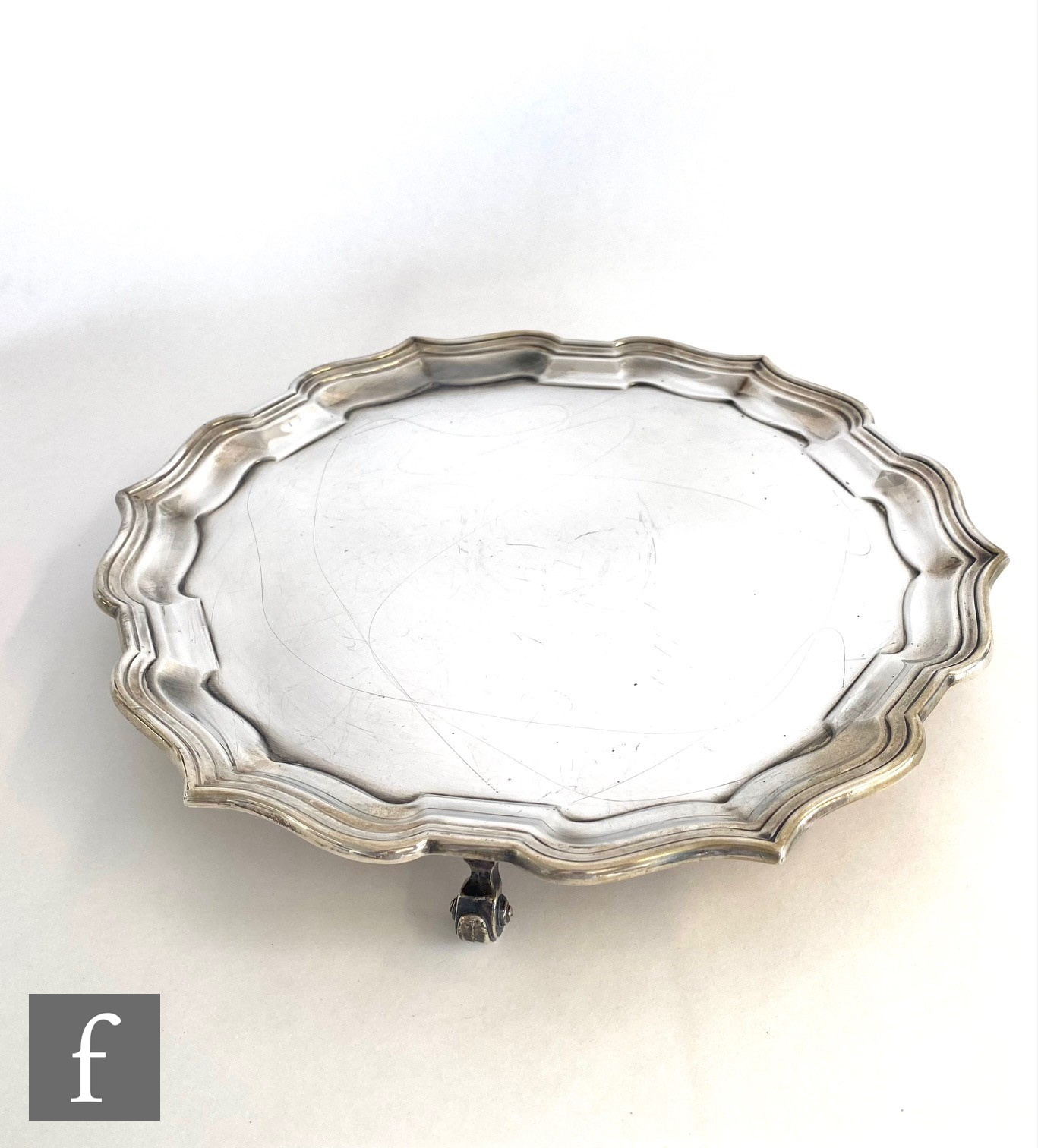 A hallmarked silver circular salver of plain form terminating in stepped scalloped border and raised