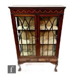 An Edwardian inlaid mahogany display cabinet enclosed by a glazed door over two short drawers