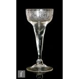 An 18th Century drinking glass circa 1740, the drawn pan top bowl engraved with foliate swags and