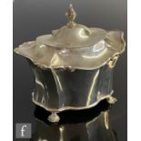 A silver hallmarked tea caddy of waisted form with faceted body, raised on four feet, with hinged