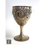A Georgian hallmarked silver goblet later decorated with embossed flowers and scrolls, height