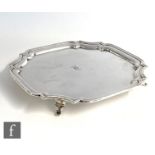 A hallmarked silver salver of plain canted square form raised on four scroll feet, diameter 27cm,