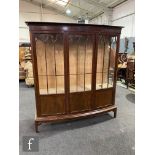 An Edwardian mahogany bowfront display cabinet enclosed by three bar glazed doors in the Chippendale