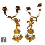 A pair of late 19th century French twin branch candelabra each modelled as putti holding separate