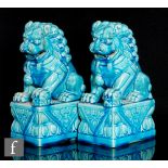 A pair of Shishi lion dogs, each raised on a high plinth with open mouths, all in a turquoise glaze,