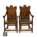 A pair of 19th Century and later oak wainscot style elbow chairs, the undulating top rails over