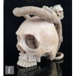 A Japanese Meiji period (1868-1912) carved ivory skull, snake and skeleton netsuke, unsigned/unknown