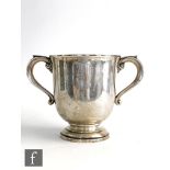 An Art Nouveau hallmarked silver two handled cup of plain form raised to a stepped foot, height