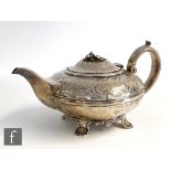 A George III hallmarked silver teapot of footed melon form with embossed floral decoration and ivory