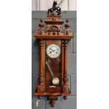 A late 19th to early 20th Century walnut cased Vienna wall clock, the pediment with moulded horse